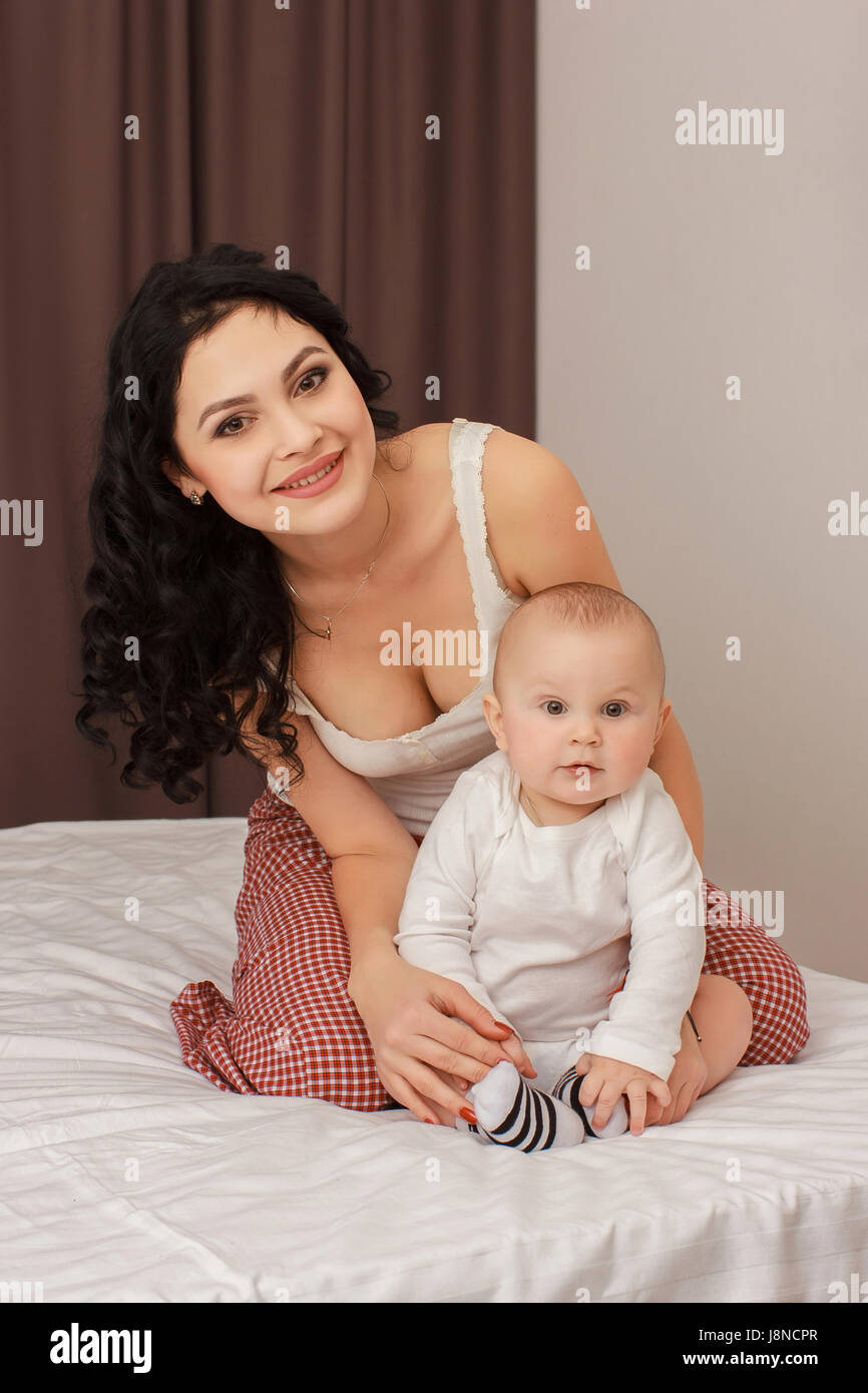 Happy smiling mother and baby lying on bed Banque D'Images