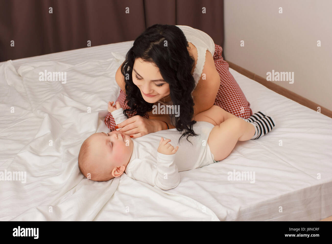 Happy smiling mother and baby lying on bed Banque D'Images