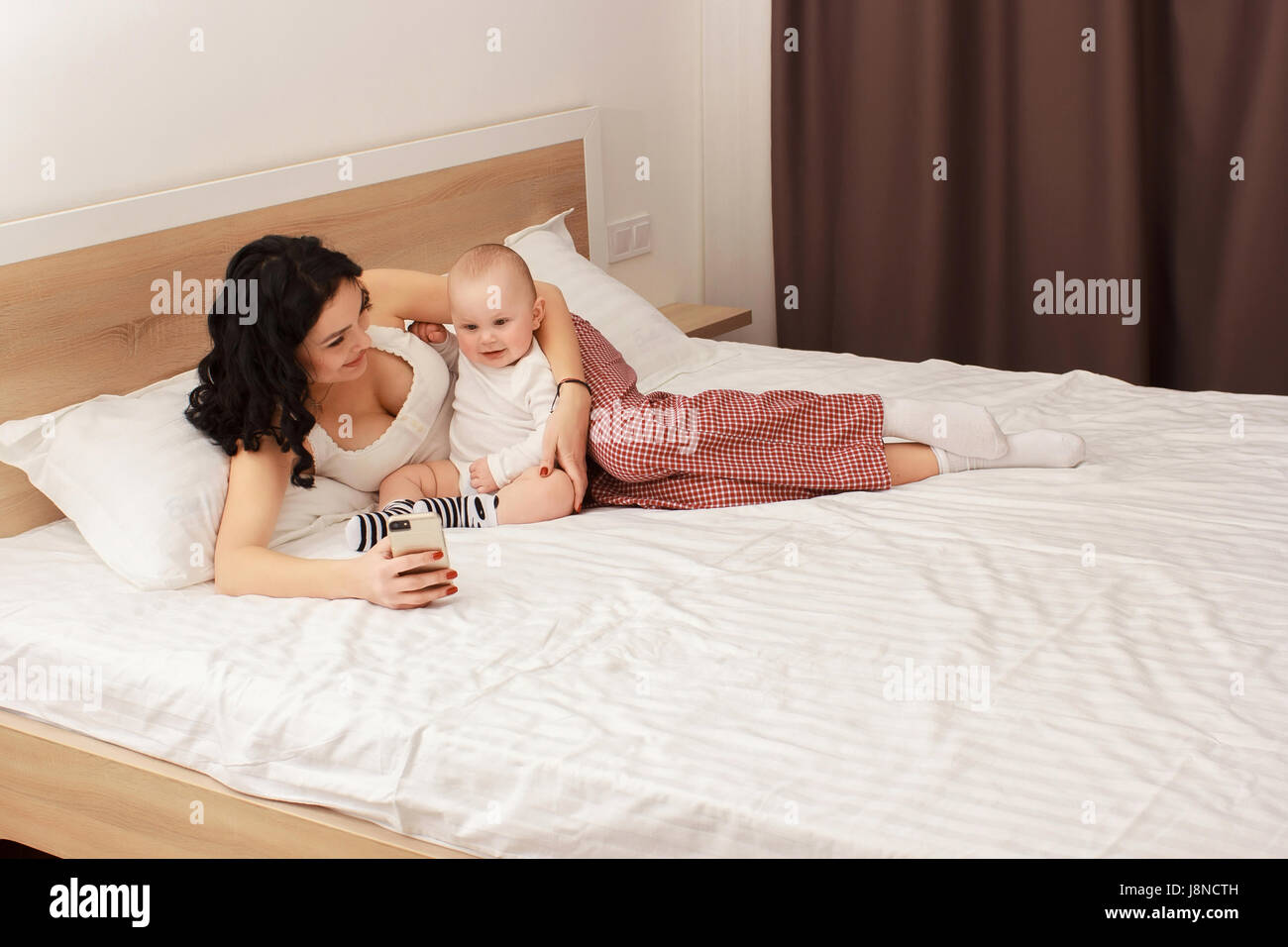 Happy smiling mother and baby lying on bed Banque D'Images