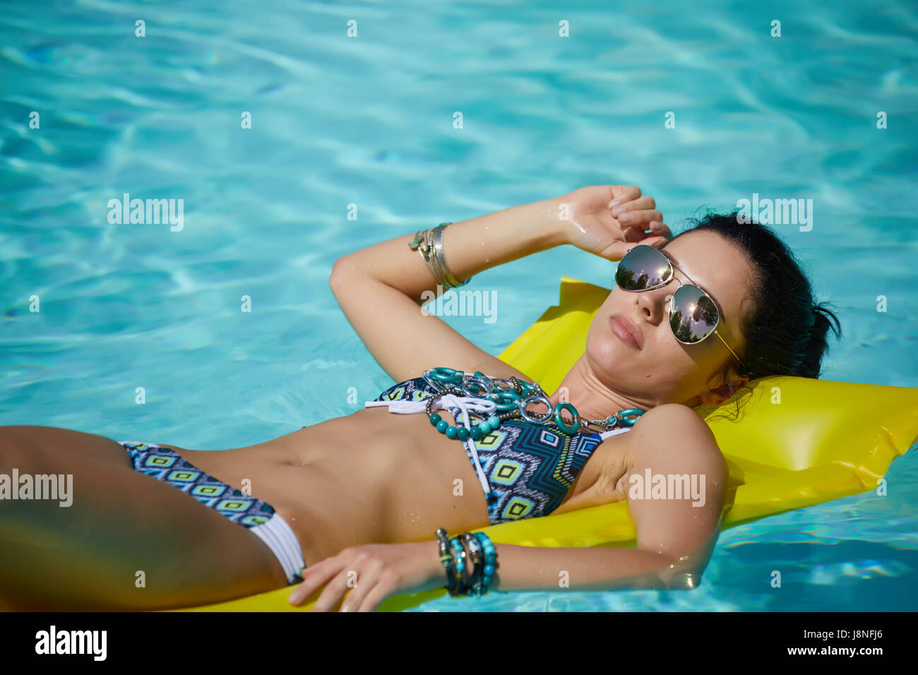 Une femme dans la piscine flotte sur un matelas soufflé Banque D'Images