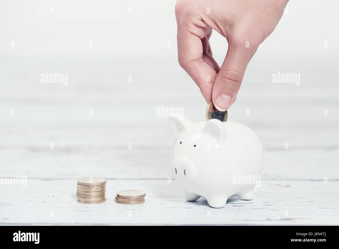 Woman Putting Coins In Piggy Bank, à l'intérieur Banque D'Images