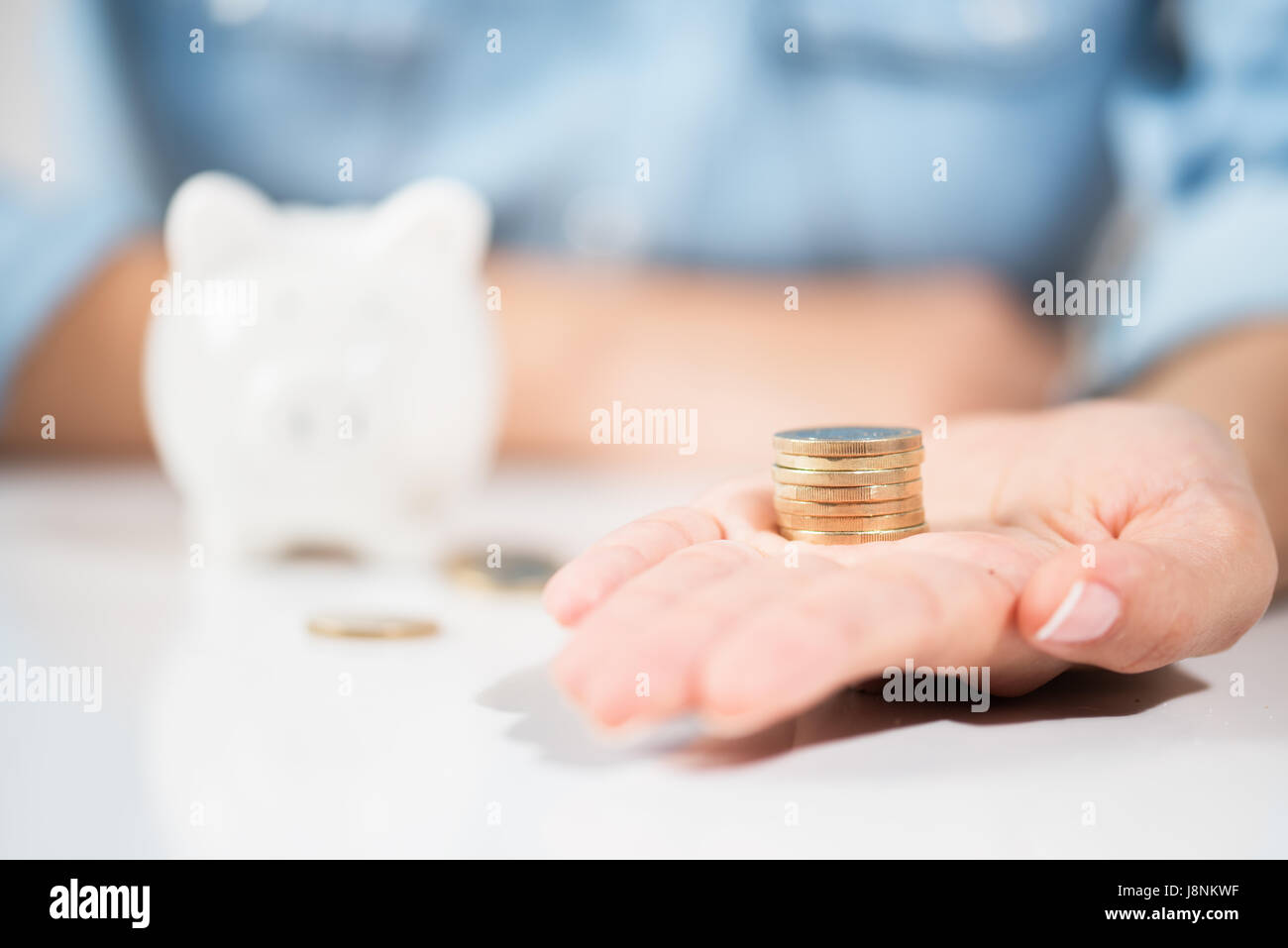 Femme tenant des pièces de monnaie pour Piggy Bank Banque D'Images