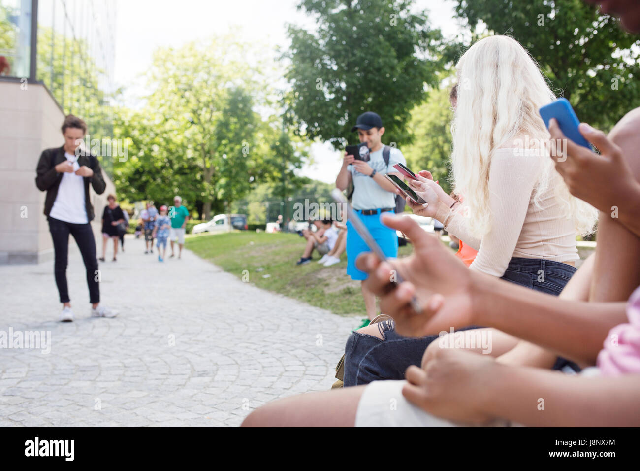 Groupe d'amis qui jouent le jeu de la réalité augmentée avec les téléphones mobiles Banque D'Images