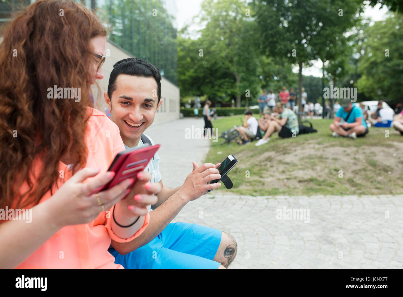 Amis jouant le jeu de la réalité augmentée avec les téléphones mobiles Banque D'Images