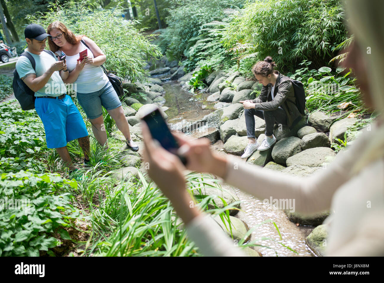 Groupe d'amis qui jouent le jeu de la réalité augmentée avec les téléphones mobiles dans le parc Banque D'Images