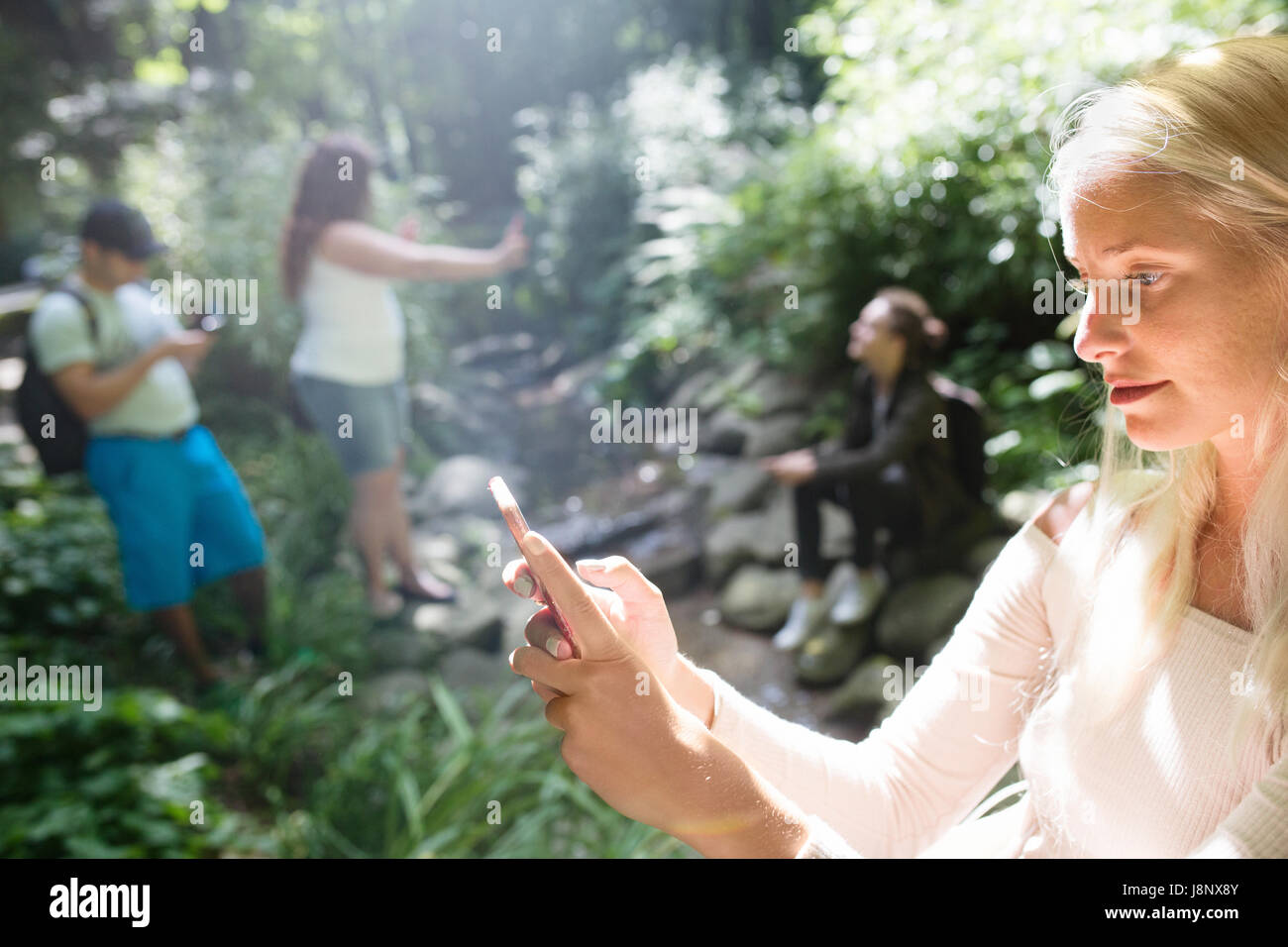 Groupe d'amis qui jouent le jeu de la réalité augmentée avec les téléphones mobiles dans le parc Banque D'Images