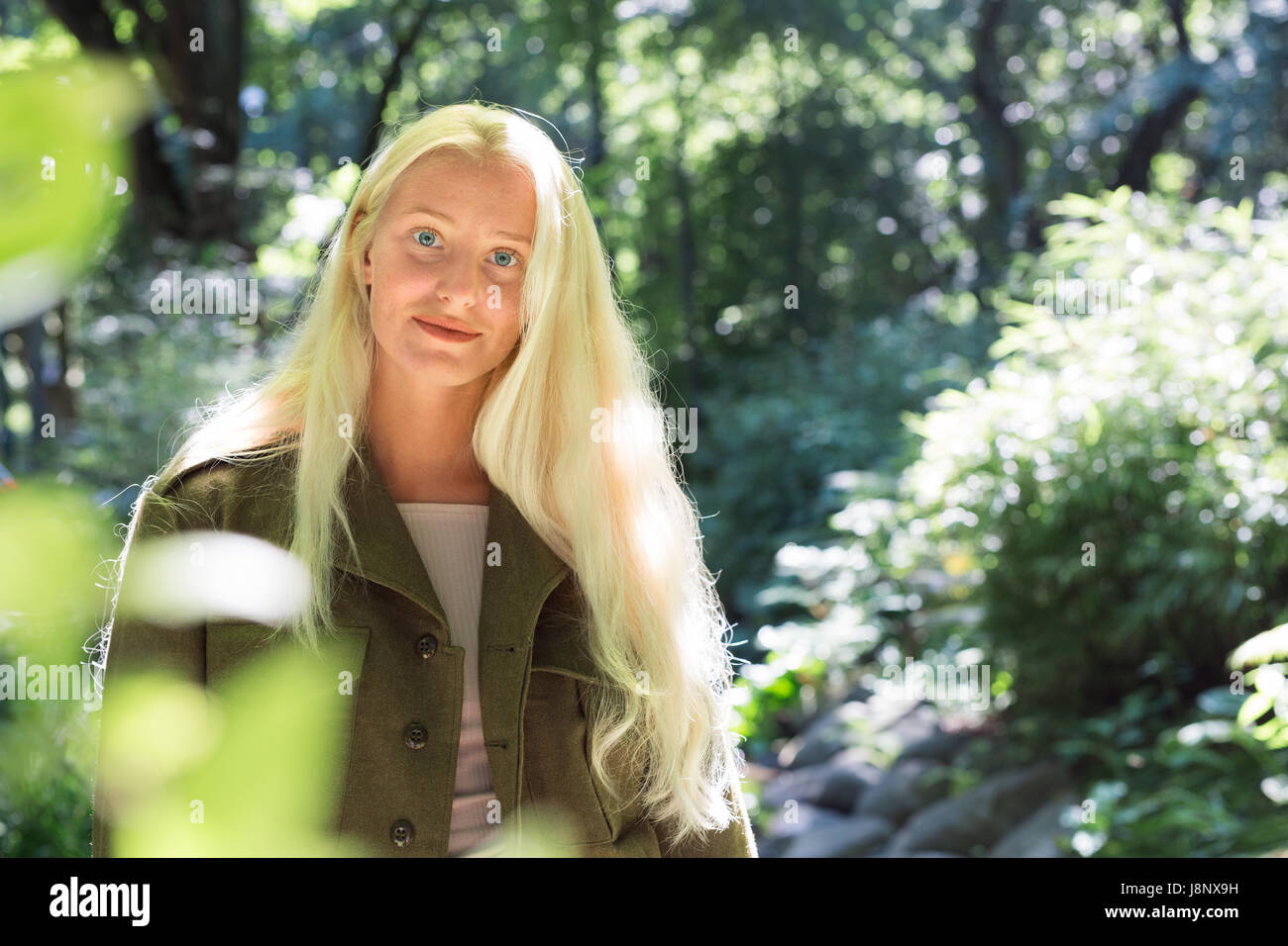 Teenage girl (16-17) entre les arbres dans le parc Banque D'Images