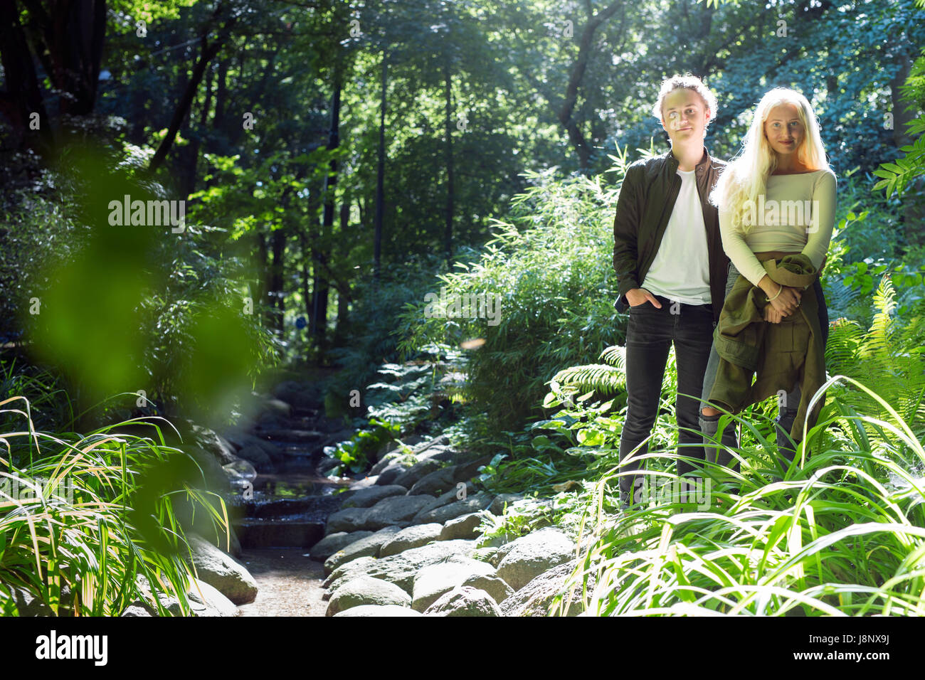 Couple (16-17) Comité permanent par stream in park Banque D'Images