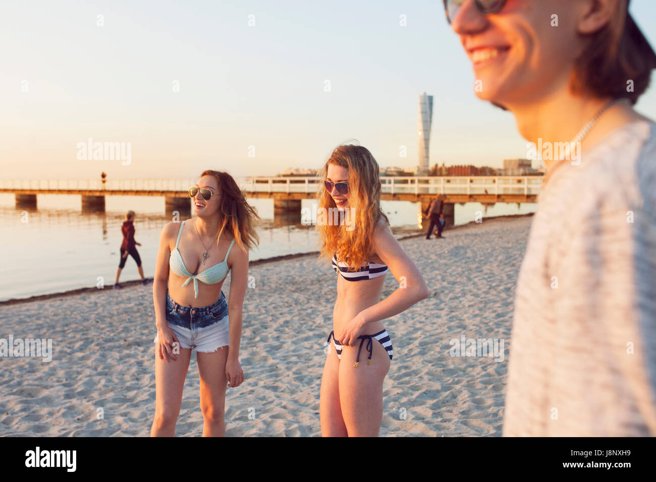 Jeune homme, jeune femme et teenage girl (16-17) smiling on beach Banque D'Images