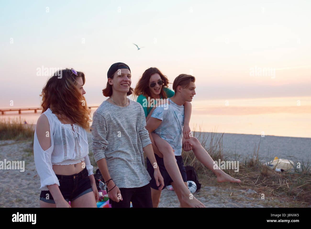 Les jeunes hommes, les jeunes femmes et teenage girl (16-17) walking on beach Banque D'Images