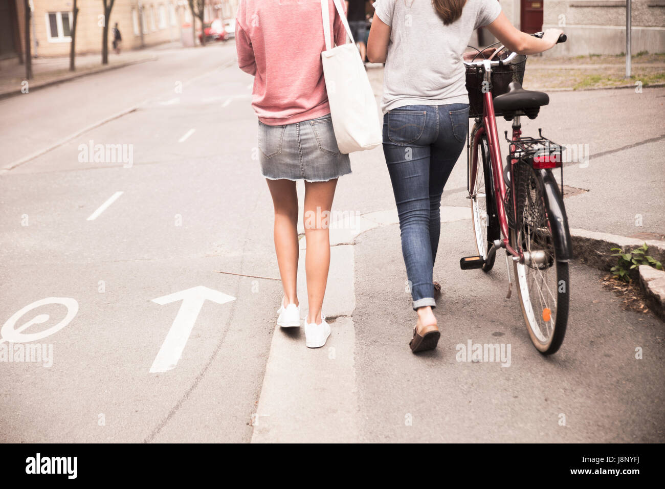 Les jeunes femmes marchant avec le vélo Banque D'Images