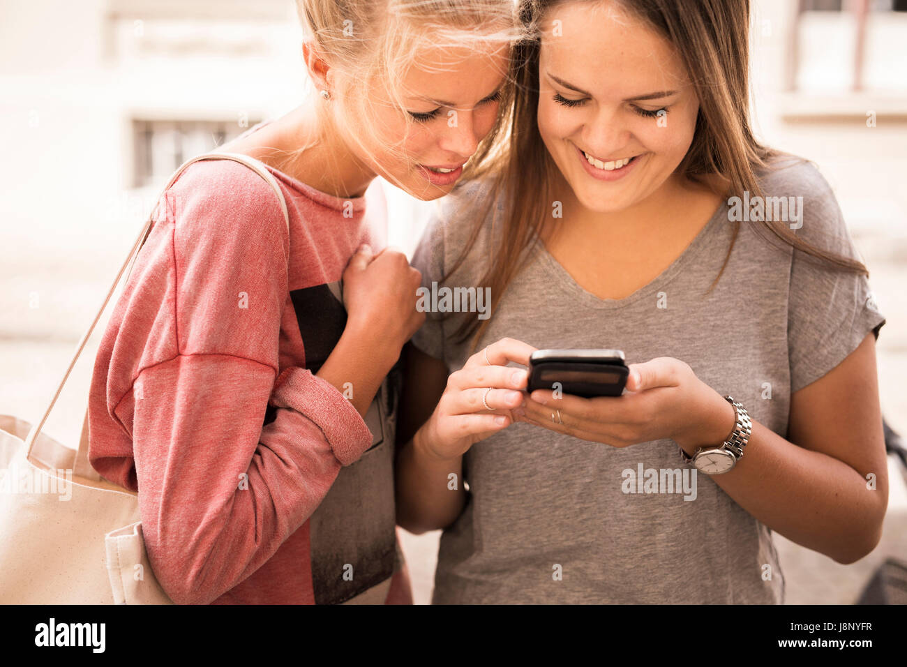 Smiling women using mobile phone Banque D'Images