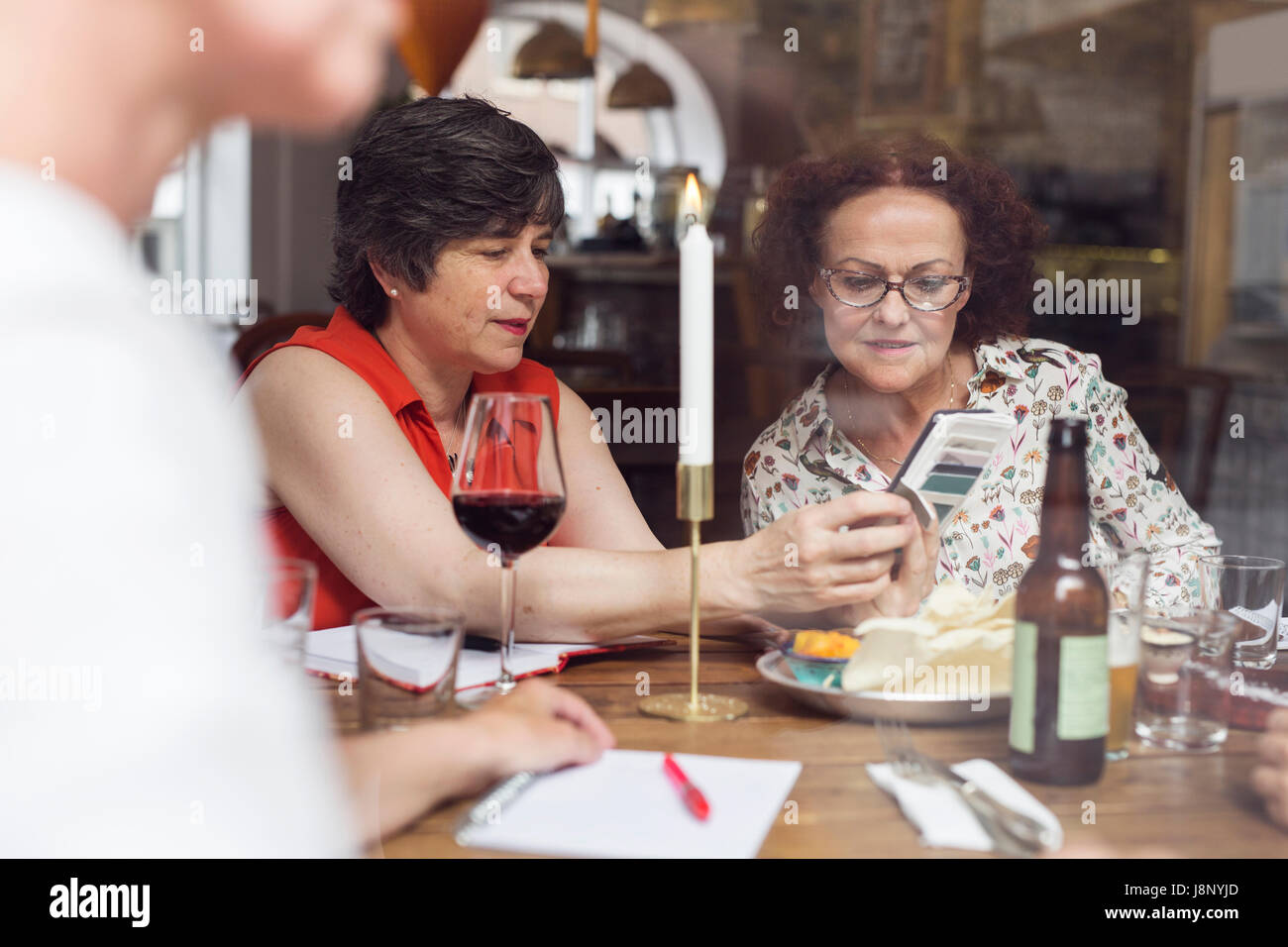 Businesswomen looking at mobile phone pendant le déjeuner au restaurant Banque D'Images