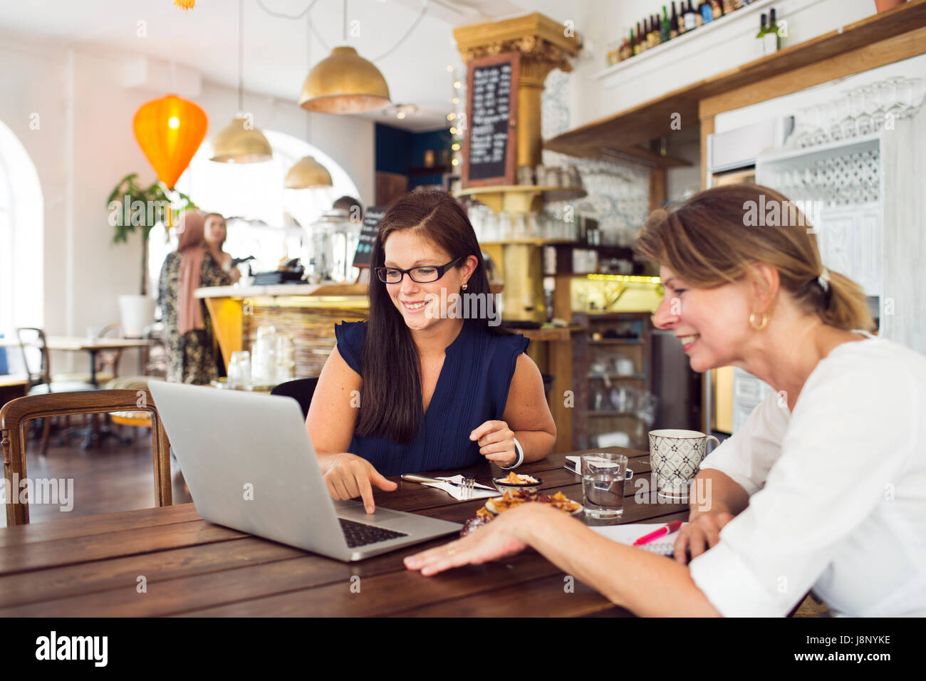 Businesswomen using laptop pendant le déjeuner au restaurant Banque D'Images