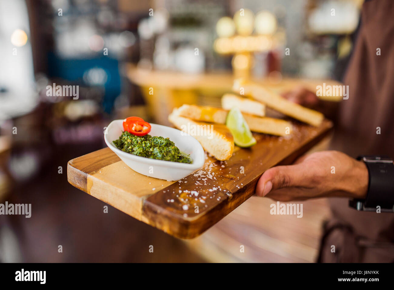 Waiter serving pain avec sauce pesto Banque D'Images