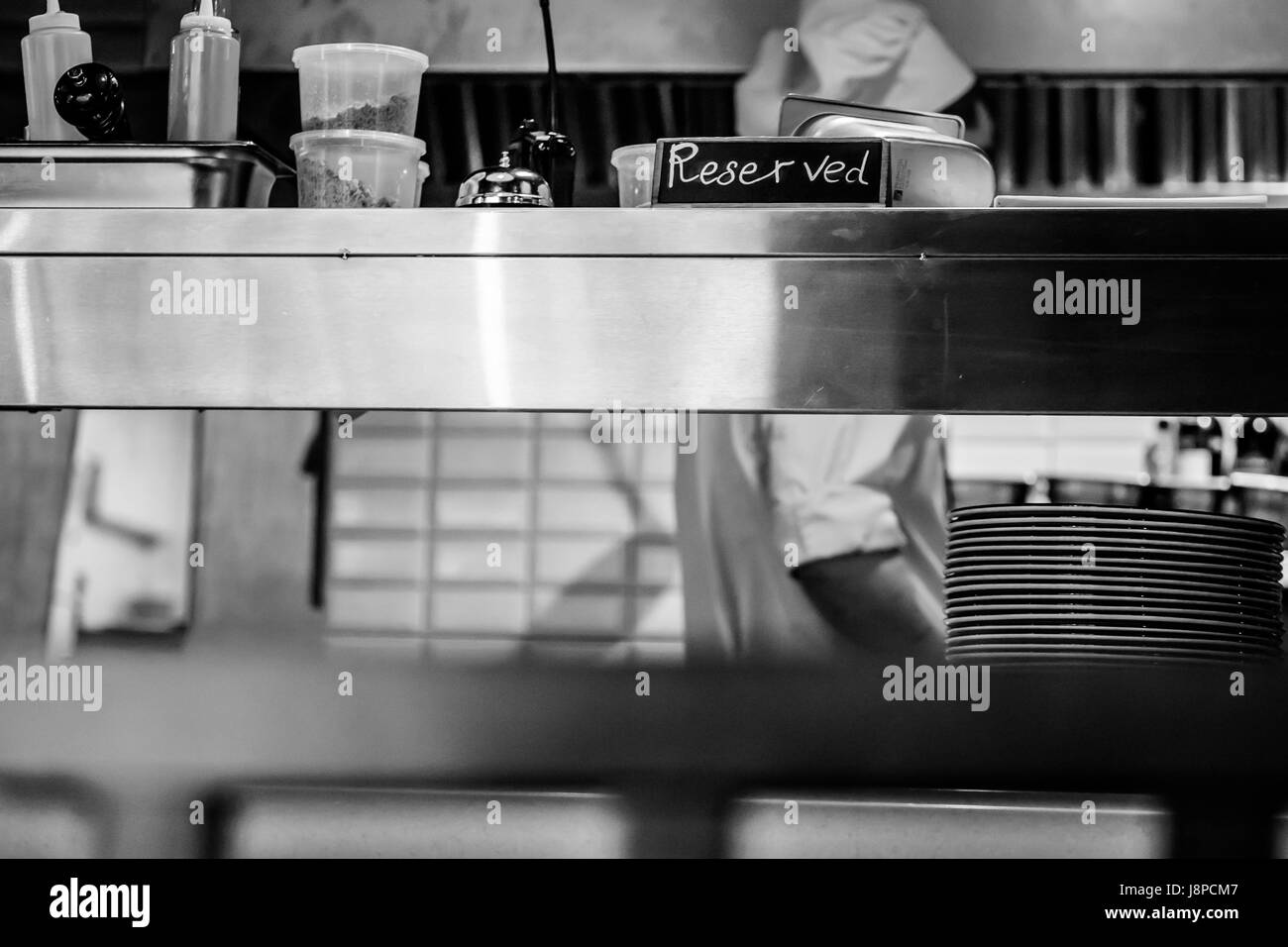Cuisine restaurant rétro close up avec table réservée et un cuisinier en chef sur l'arrière-plan. Le noir et blanc Banque D'Images