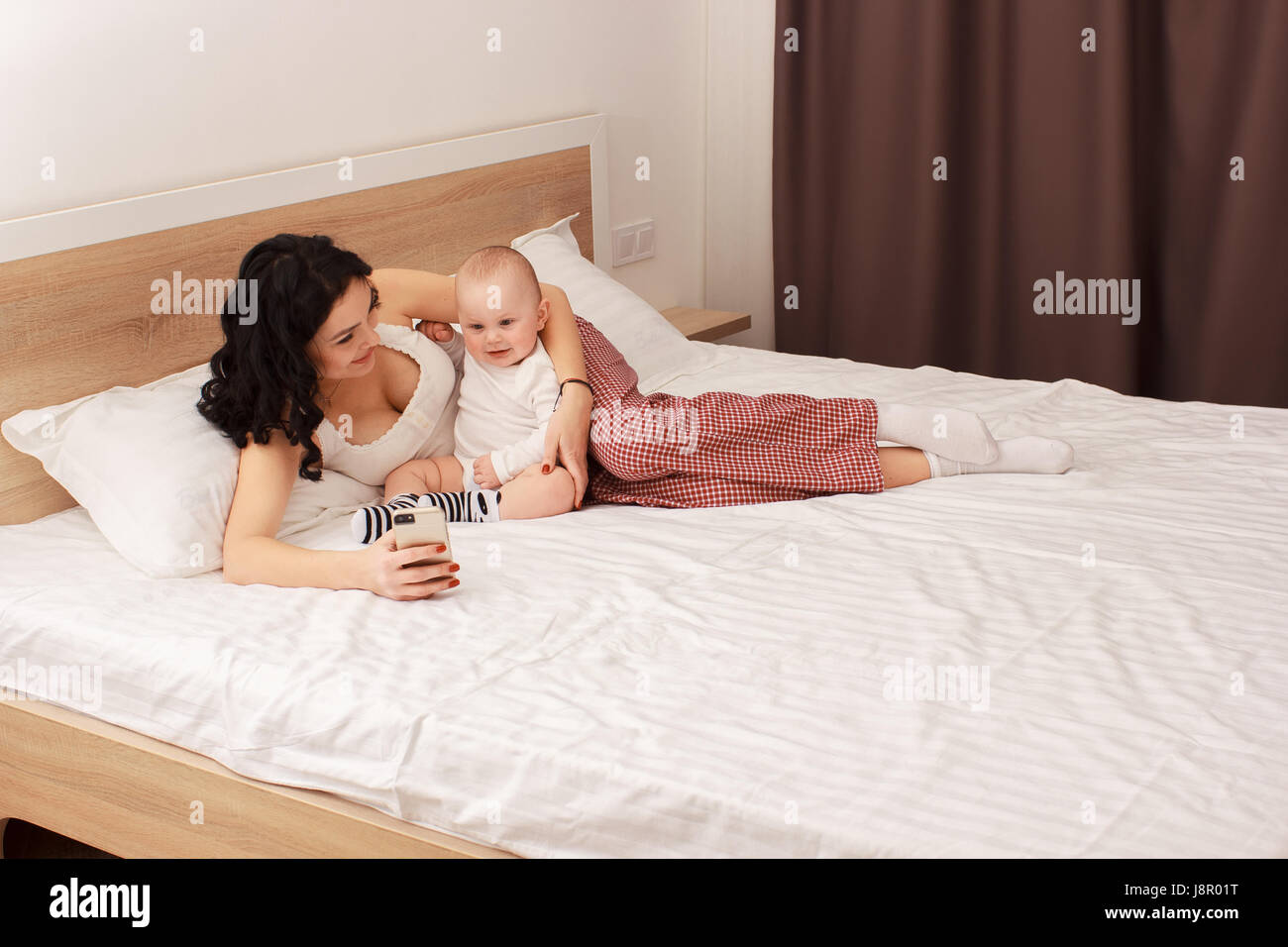 Happy smiling mother and baby lying on bed Banque D'Images