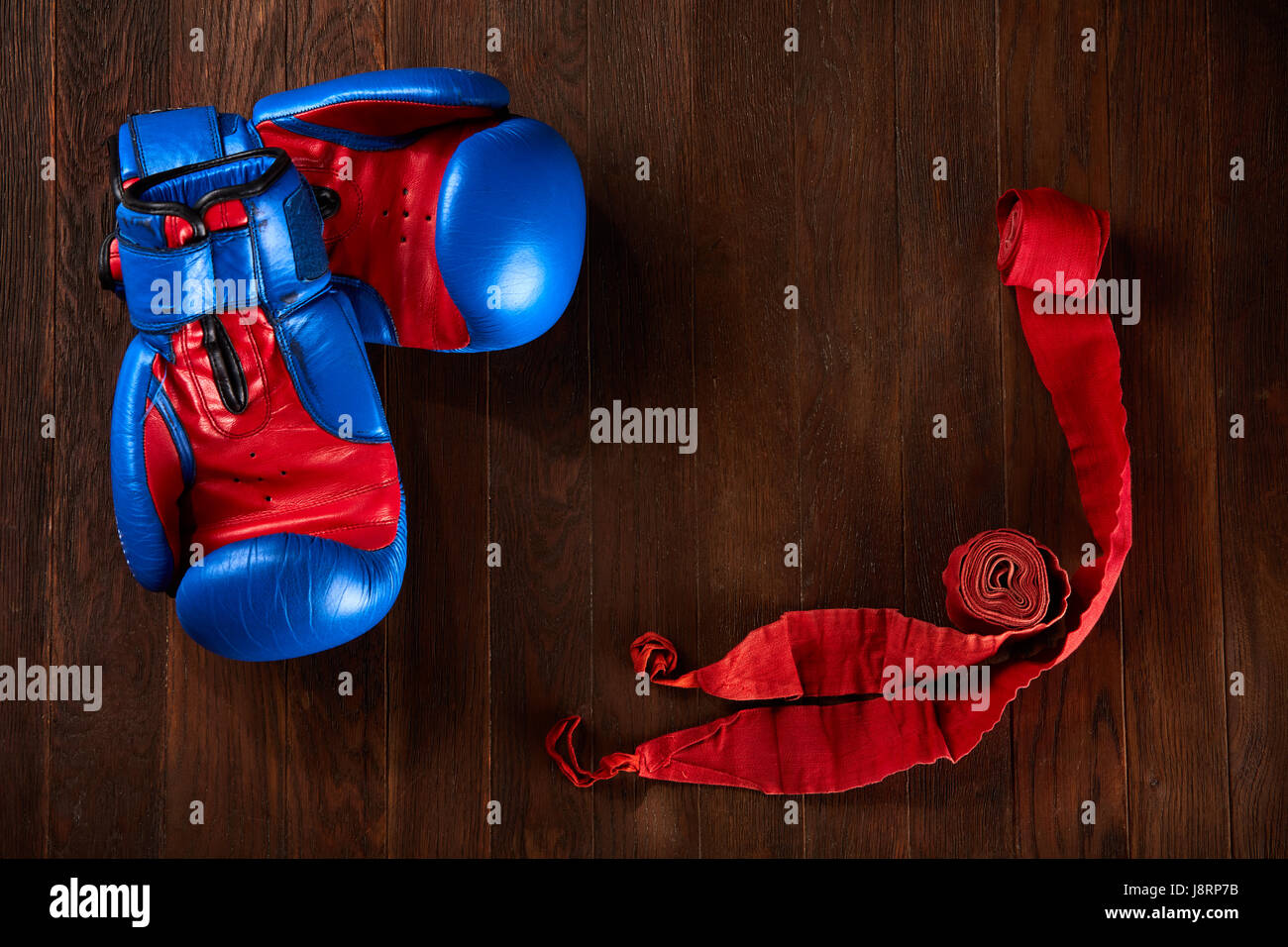 Arrière-plan de Sport bleu et rouge avec des gants et un bandage rouge sur fond de bois. Banque D'Images