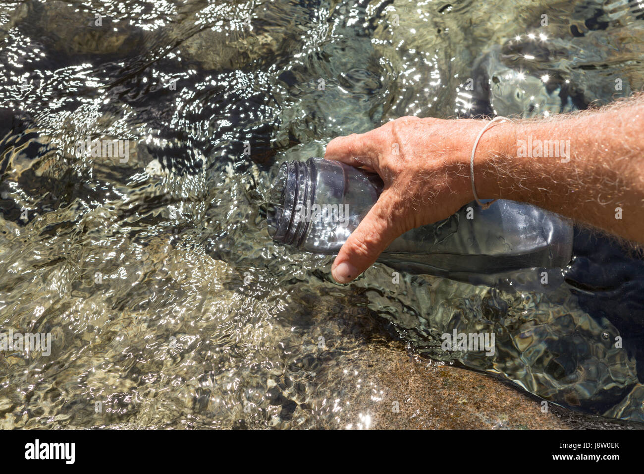Remplir une bouteille d'eau dans un ruisseau clair en Nouvelle-Zélande fiordland Banque D'Images