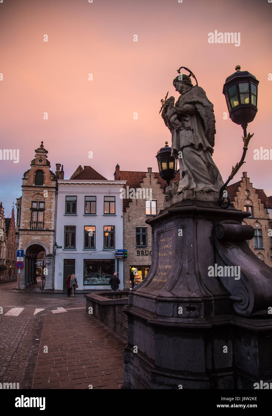 Une statue et lampe guard l'un des ponts de Bruges, Belgique, au coucher du soleil. Banque D'Images