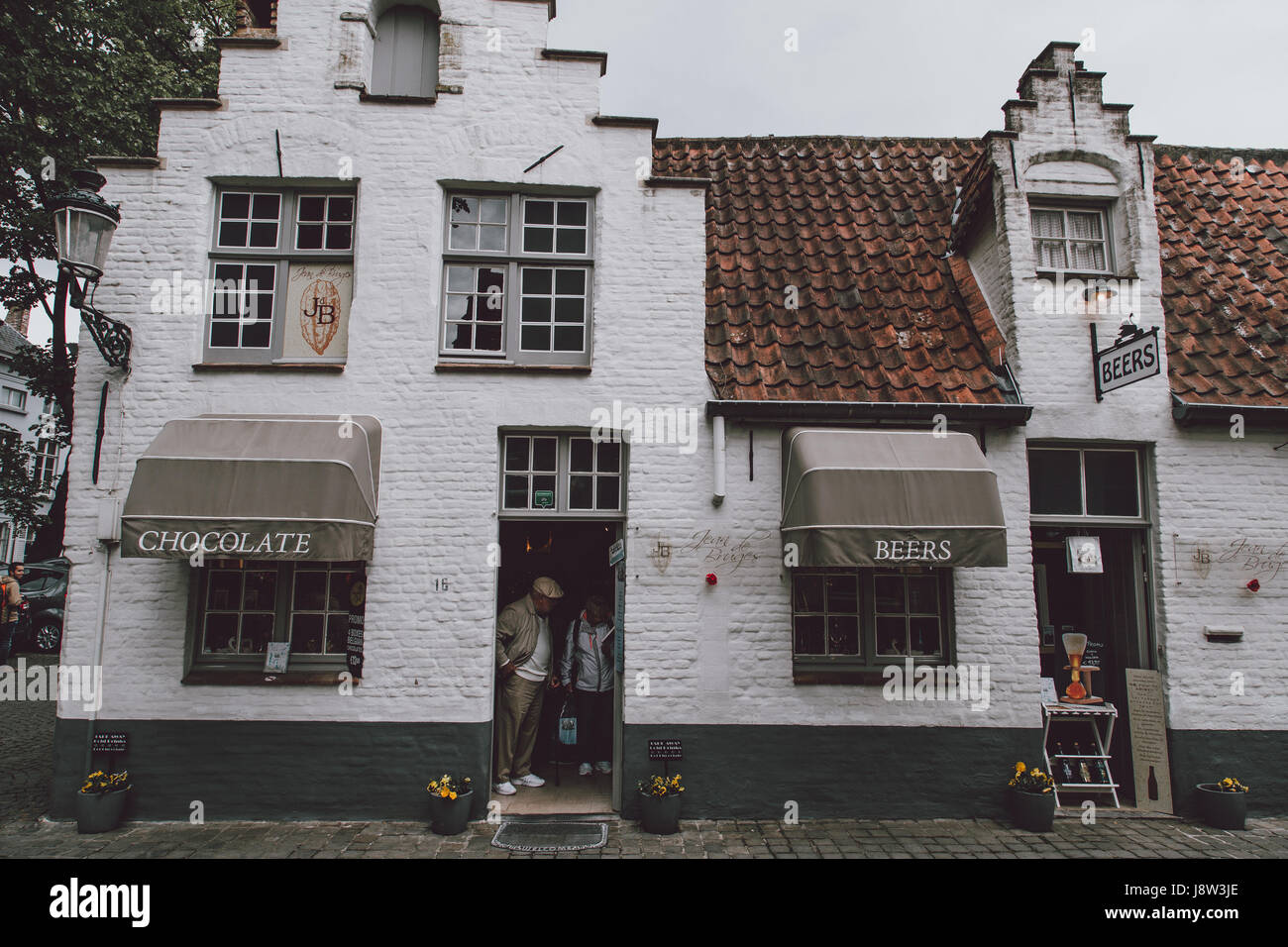 Côte à côte, magasins de chocolat et de bière, deux des principales spécialités locales à Bruges, Belgique, dans l'habitat traditionnel. Banque D'Images