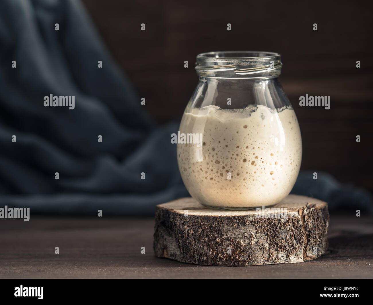 Levain Blé actif dans un bocal en verre sur fond de bois brun. Démarreur pour pain au levain. La tonalité de l'image. Copier l'espace. Banque D'Images