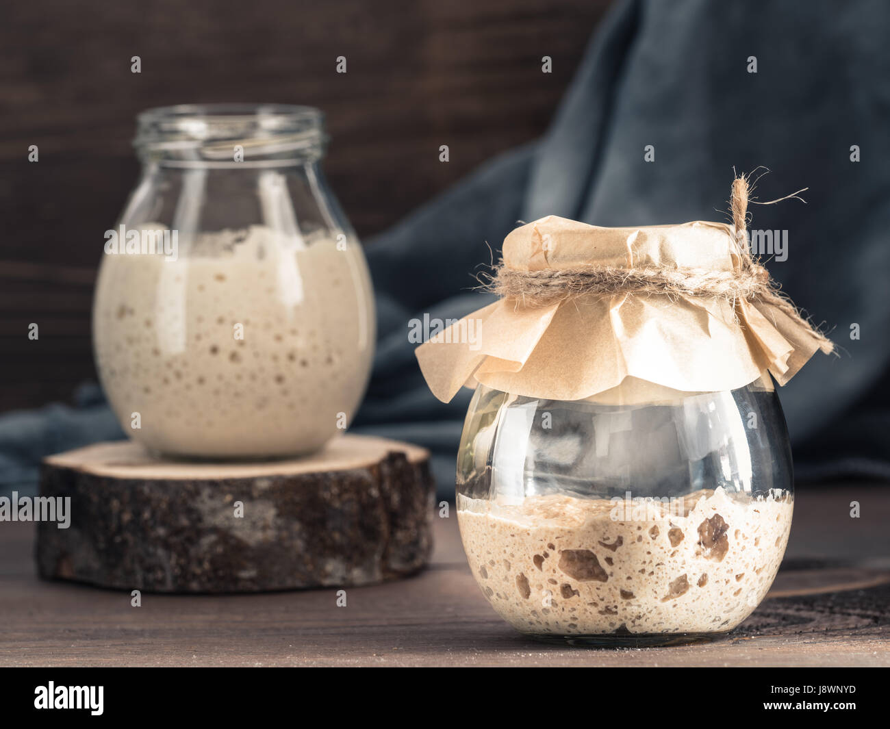 Levain de seigle active du démarreur dans le bocal en verre brun sur fond de bois. Démarreur pour pain au levain. La tonalité de l'image. Copier l'espace. Banque D'Images