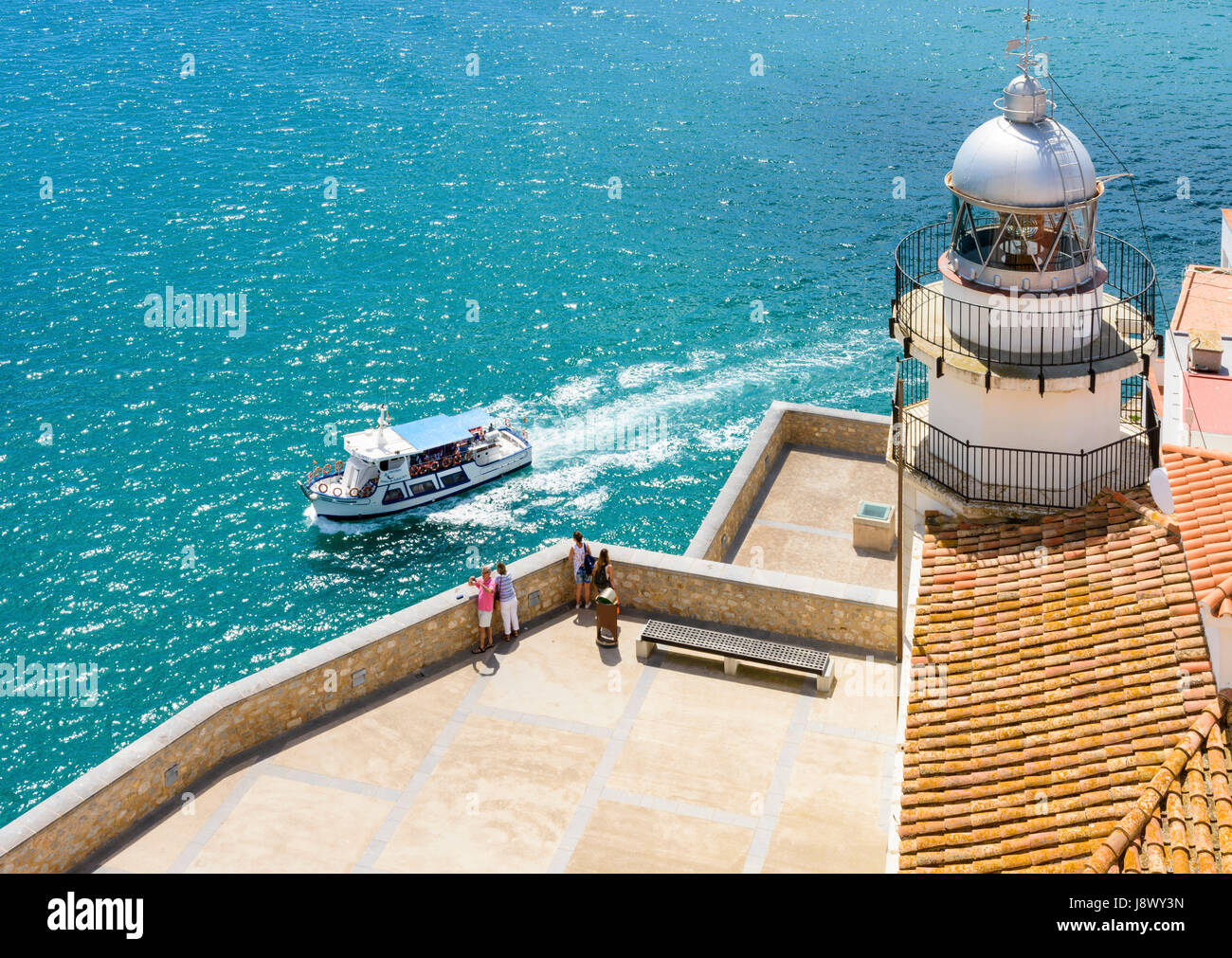 Bateau de tourisme passe le phare et la péninsule de la vieille ville de Peniscola, Espagne Banque D'Images