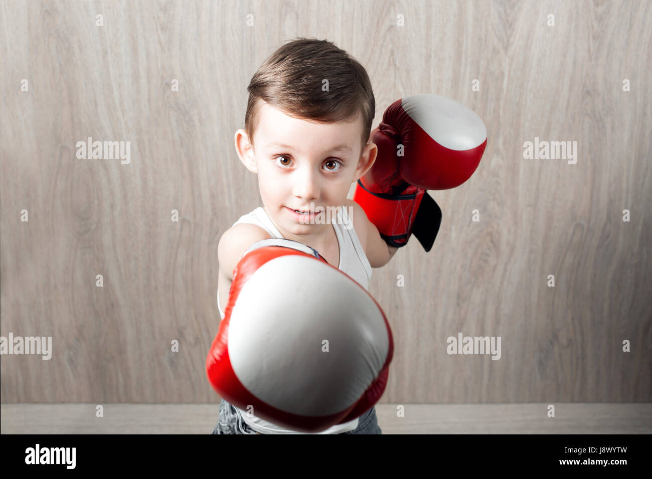 Cute little boy with boxing gloves grande taille. Portrait d'un enfant se  livrant à un sportif fort. le bouffon et pas graves. fond de bois Photo  Stock - Alamy