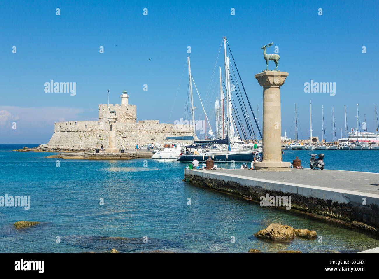 RHODES, GRÈCE - 13 juin 2015 : les personnes dans le port de Mandraki port observant deer statues et Fort Saint Nicolas avec le phare à Rhodes, Grèce Banque D'Images