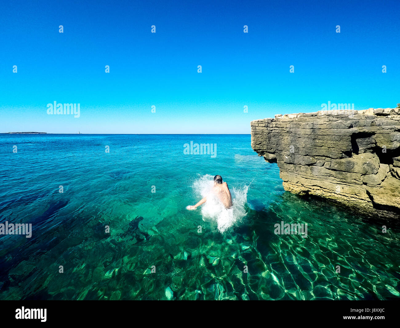 Heureux garçon sautant dans la mer croate Banque D'Images