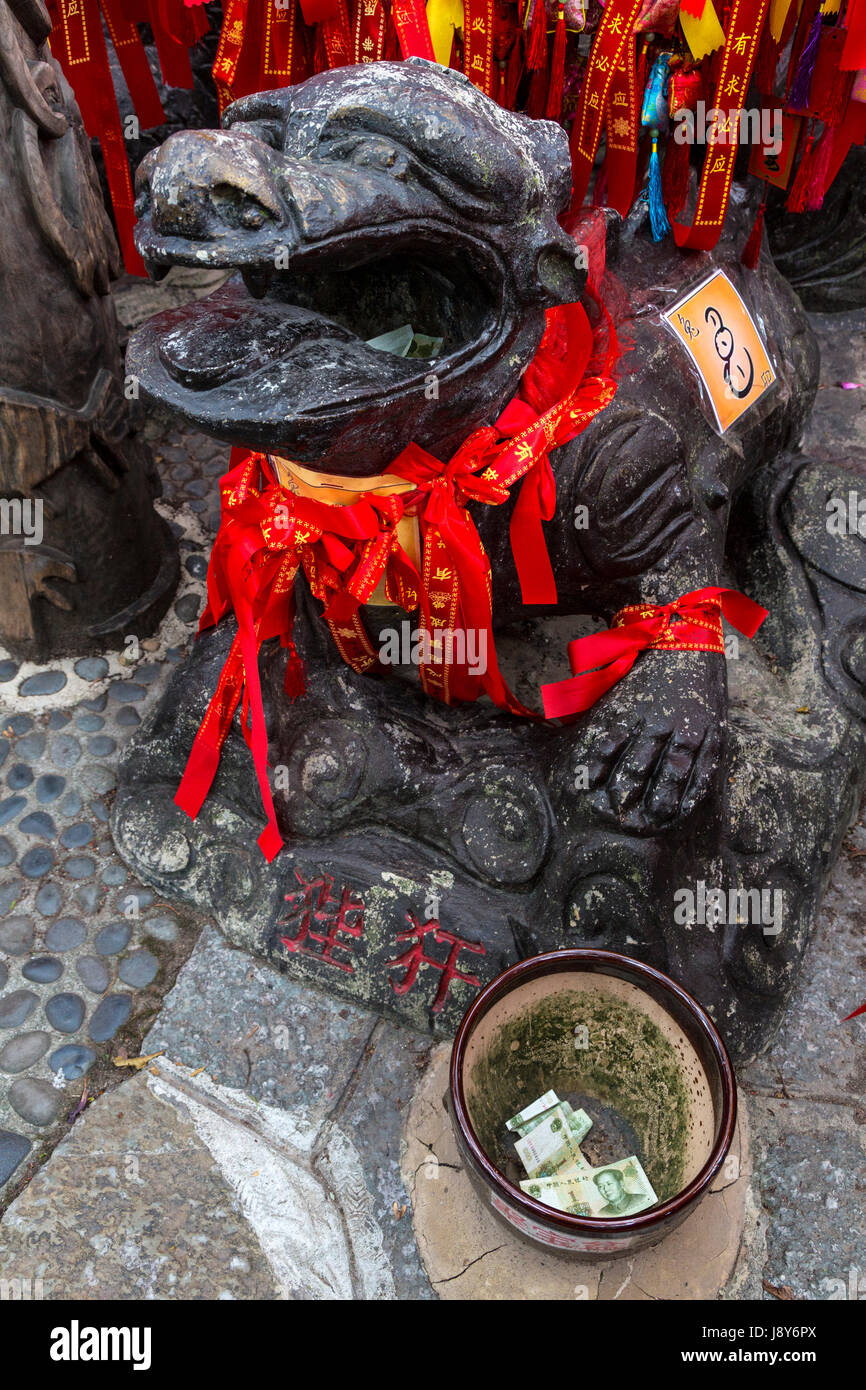 Guilin, Chine. Elephant Trunk Hill Park. Rubans rouges accrochés sur Zodiac Figure demandant un souhait. L'épargne dans un bol. Banque D'Images