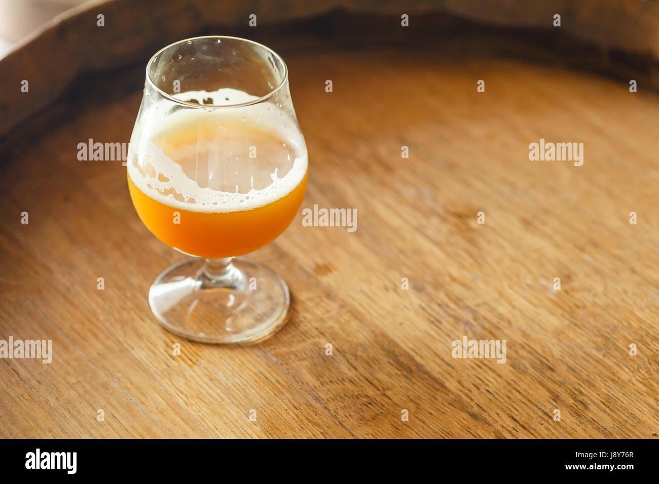 Verre de bière de blé debout sur un tonneau en bois dans une brasserie Banque D'Images