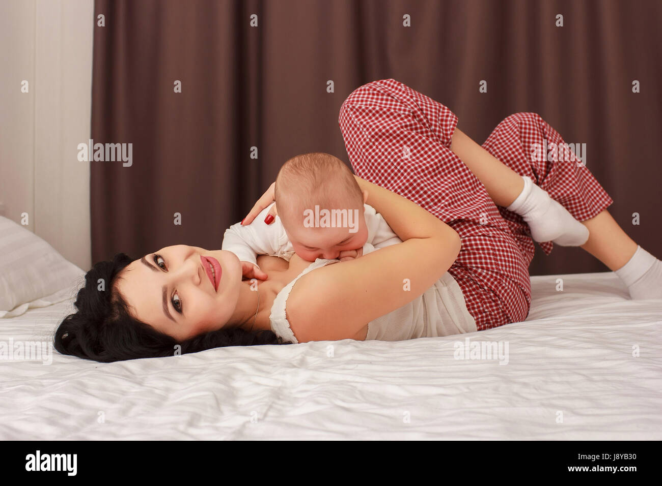 Happy smiling mother and baby lying on bed Banque D'Images