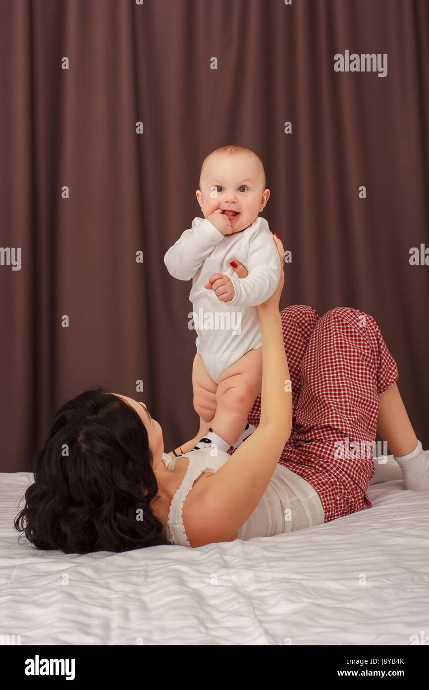 Happy smiling mother and baby lying on bed Banque D'Images