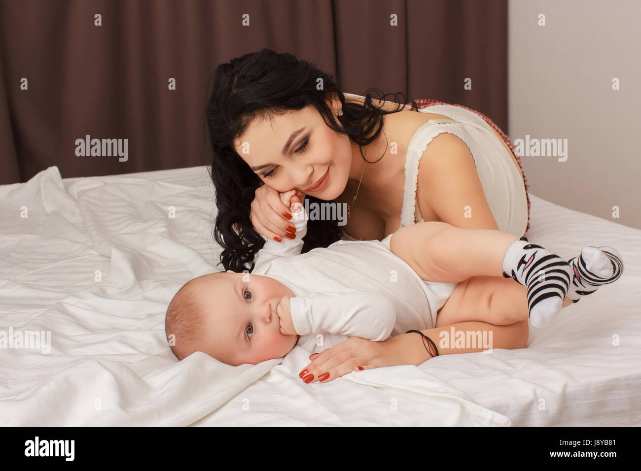 Happy smiling mother and baby lying on bed Banque D'Images