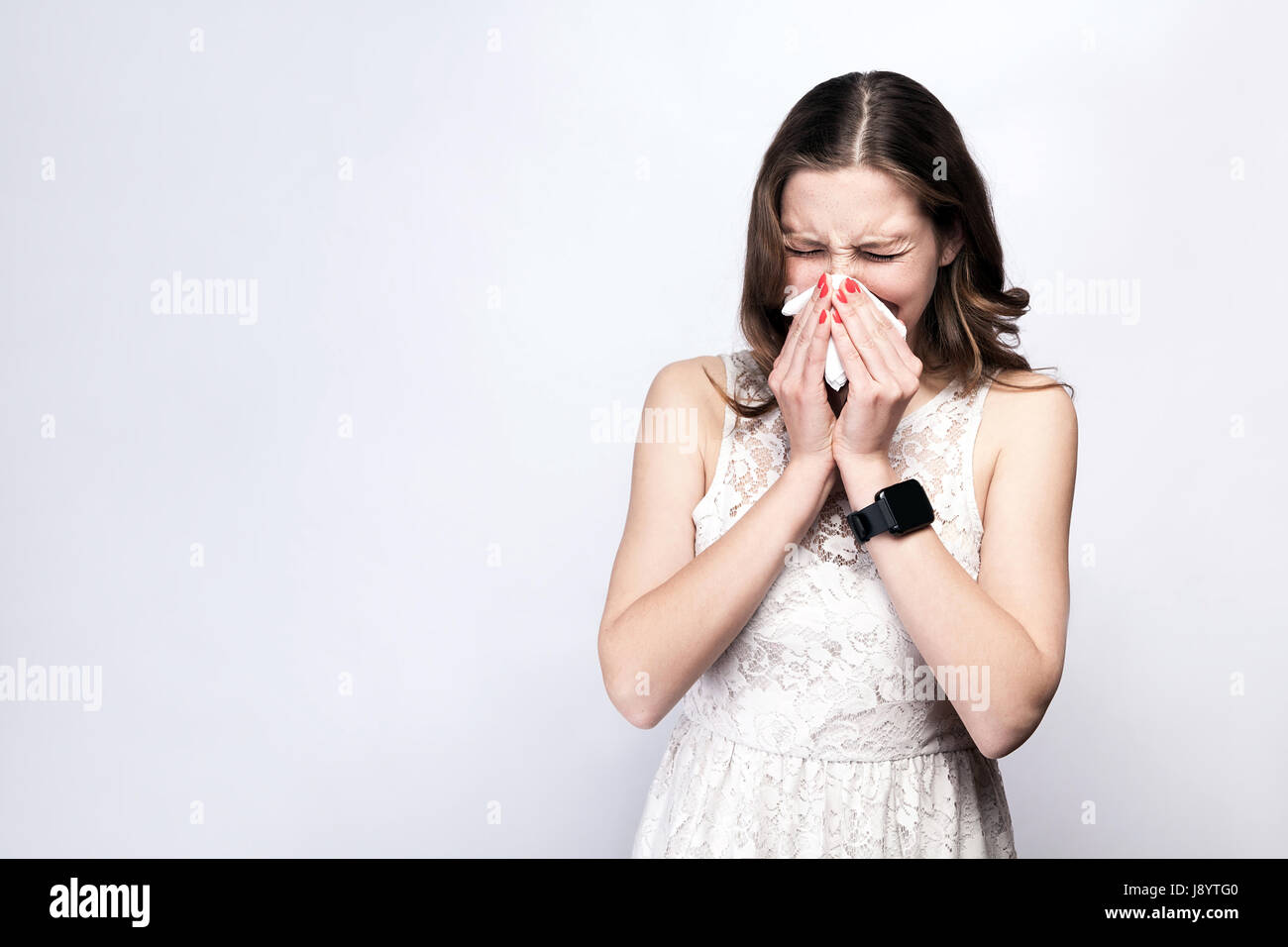 Portrait de femme froide malade avec des taches de rousseur et robe blanche et smart watch sur fond gris argent. santé et médecine concept. Banque D'Images