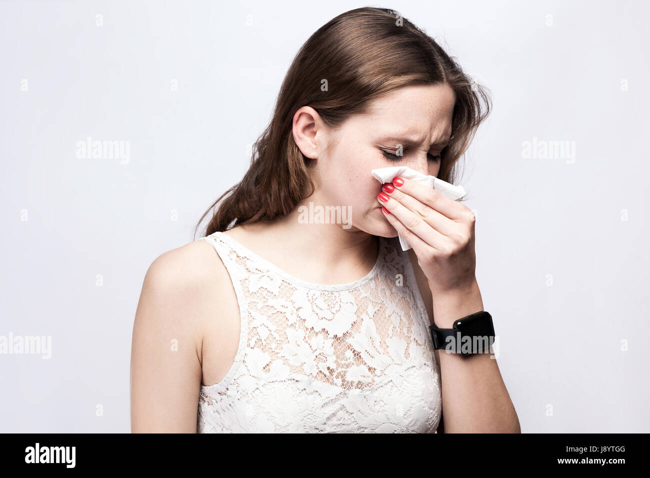 Portrait de femme froide malade avec des taches de rousseur et robe blanche et smart watch sur fond gris argent. santé et médecine concept. Banque D'Images