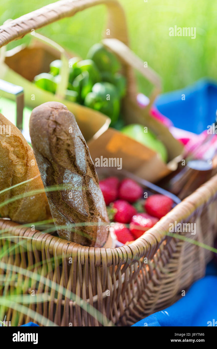 Panier pique-nique pour l'été avec du vin, du pain, des fruits et des collations on Green grass in park. Selective focus Banque D'Images
