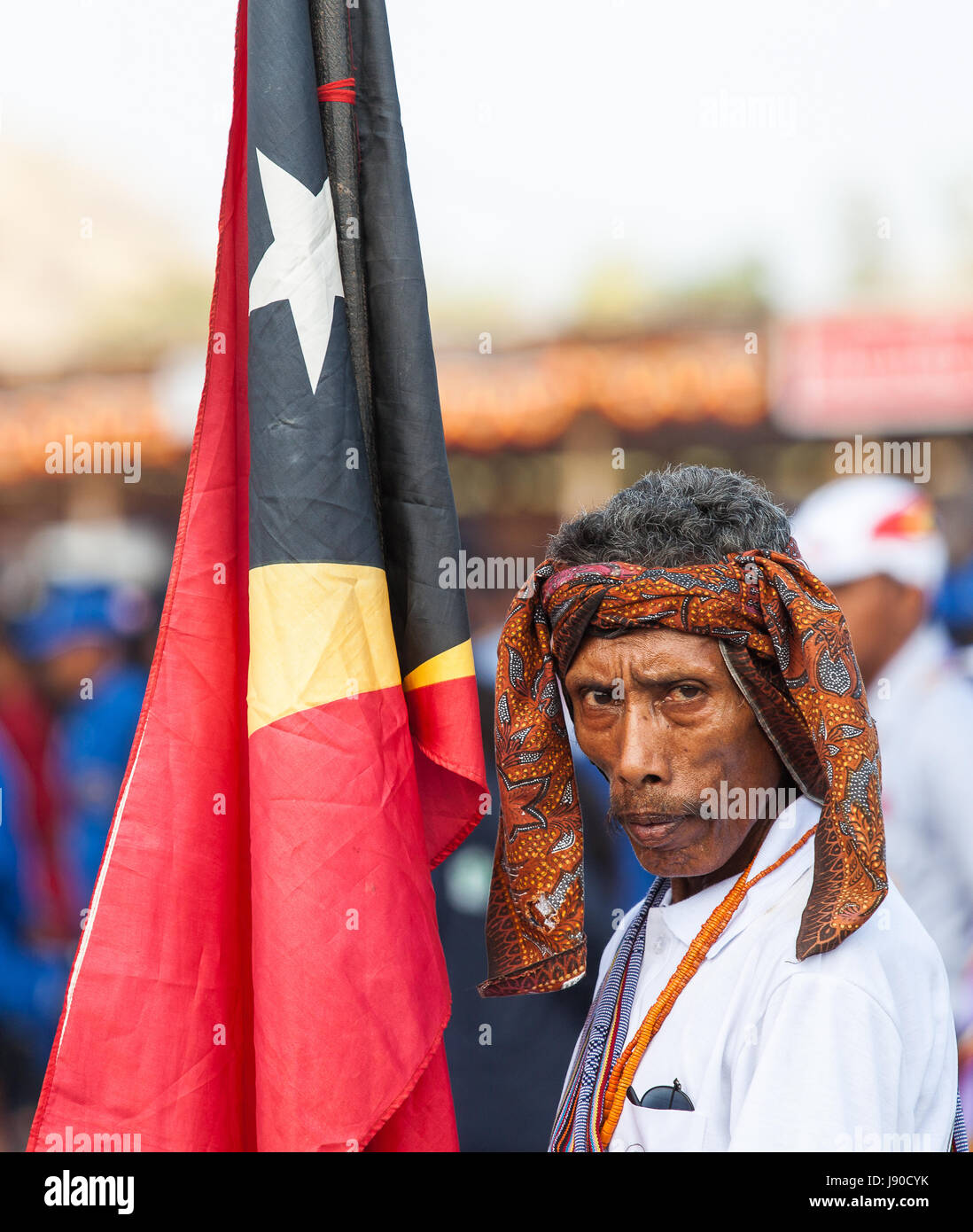 Dili, Timor oriental. L'homme en costume traditionnel tenant un drapeau du Timor oriental Banque D'Images