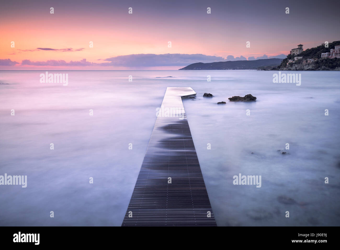 Castiglioncello destination, jetée en bois dans la baie, des rochers et de la mer sur le coucher du soleil. La Toscane, Italie, Europe. L'exposition longue Banque D'Images