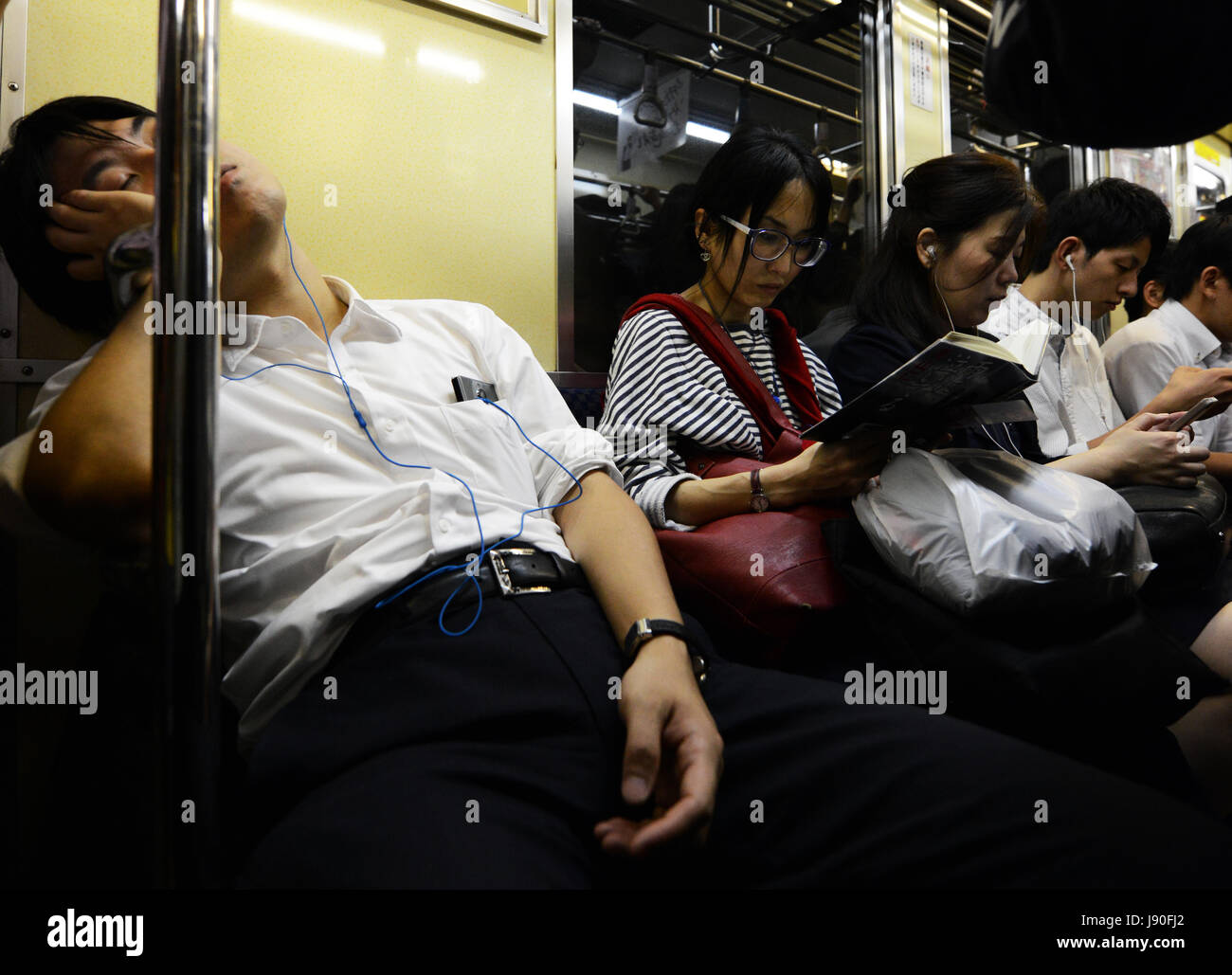 Les passagers assis dans un train de métro de Tokyo. Banque D'Images