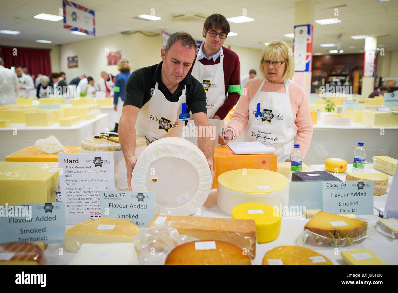 Un juge lève toute une roue de fromage dur recouverte de tissu pour vérifier l'aspect et la rondeur des British Cheese Awards au Royal Bath & West show à Somerset, Où plus de 1,000 fromages britanniques se disputent le titre de champion suprême lors d'un événement conçu pour être une « grande célébration » de l'industrie. Banque D'Images