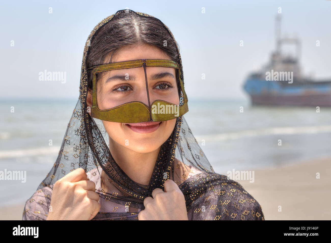 Jeune femme iranienne en masque traditionnel des femmes musulmanes dans le  sud de l'Iran, smiling, debout sur la rive du golfe Persique, dans la  province d'Hormozgan, cl Photo Stock - Alamy