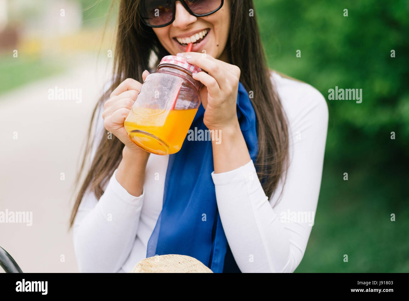 Femme de détente et de boire du jus d'orange froid Banque D'Images