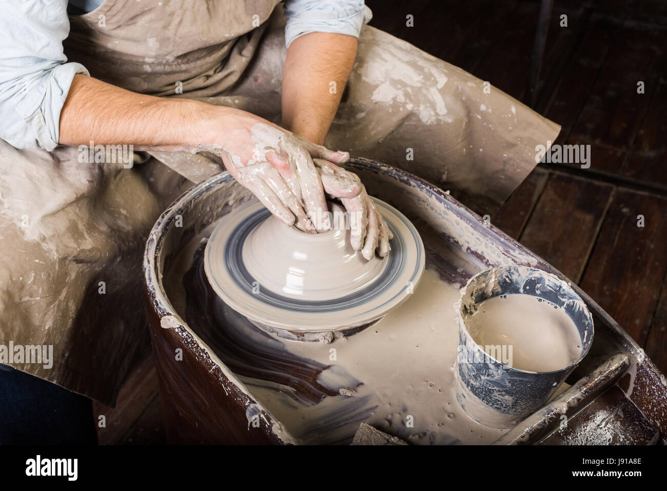 Atelier de poterie, céramique, concept art - close-up sur le travail de  potier avec l'argile brute et l'homme les mains, un homme sculpt un  ustensile avec les doigts, maître en tablier, vue