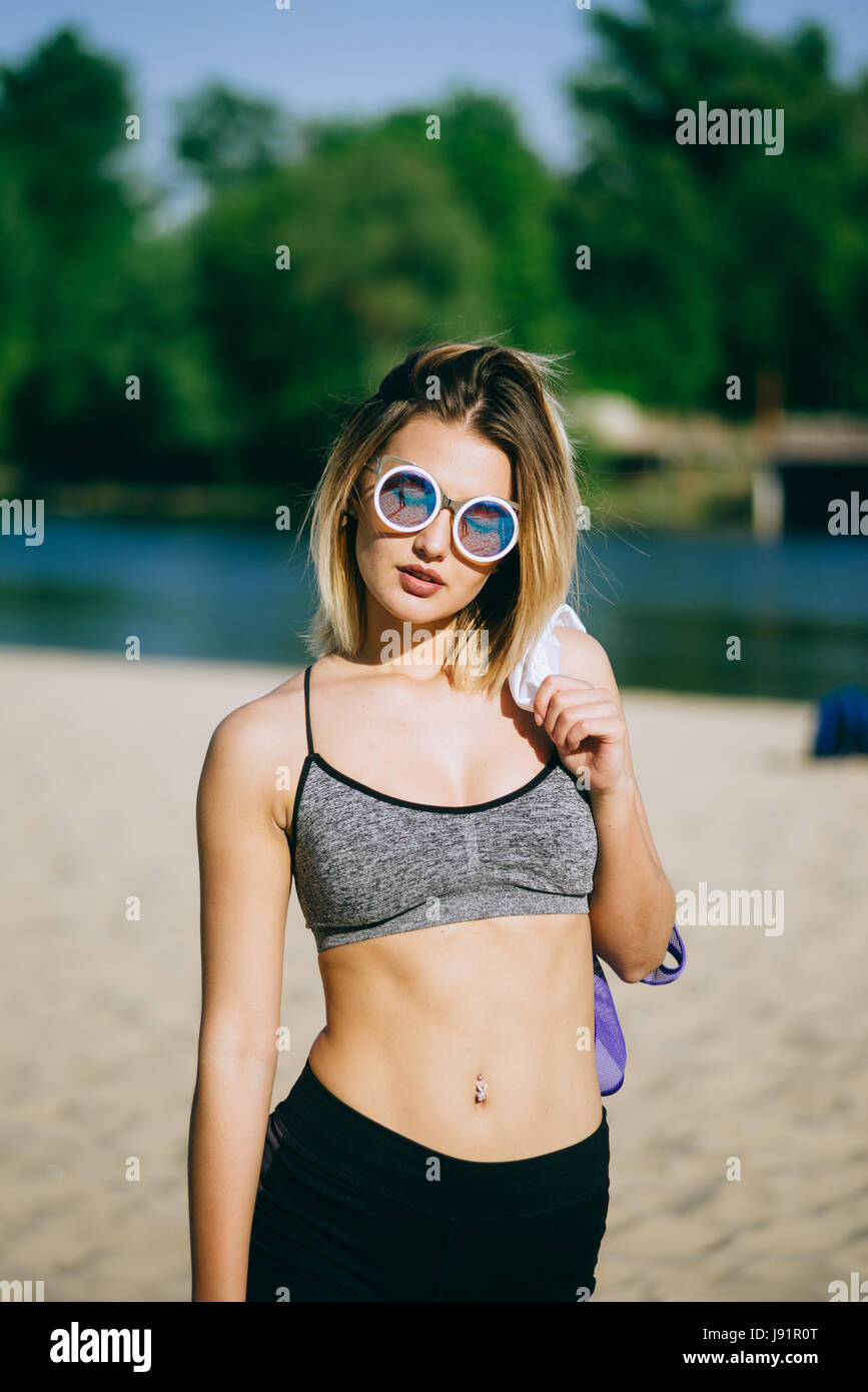 Très belle jeune fille blonde sexy pose pour la caméra dans une plage publique après la formation avec look sportif Banque D'Images