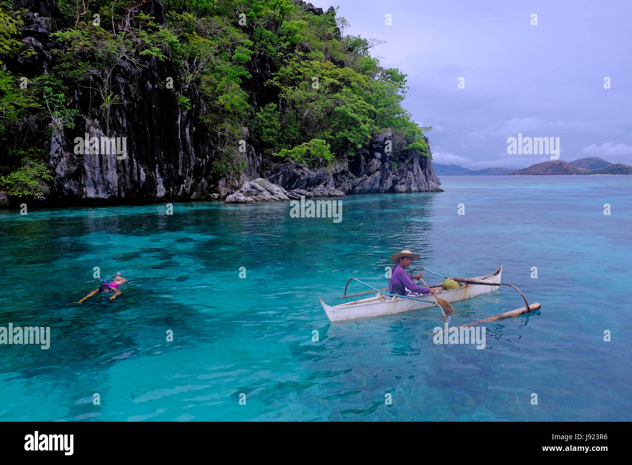 Un pêcheur dans un bateau à l'outrigger banka le sud de la Chine le long de la mer l'île de Coron dans l'Îles Calamian dans le nord de Palawan des Philippines Banque D'Images