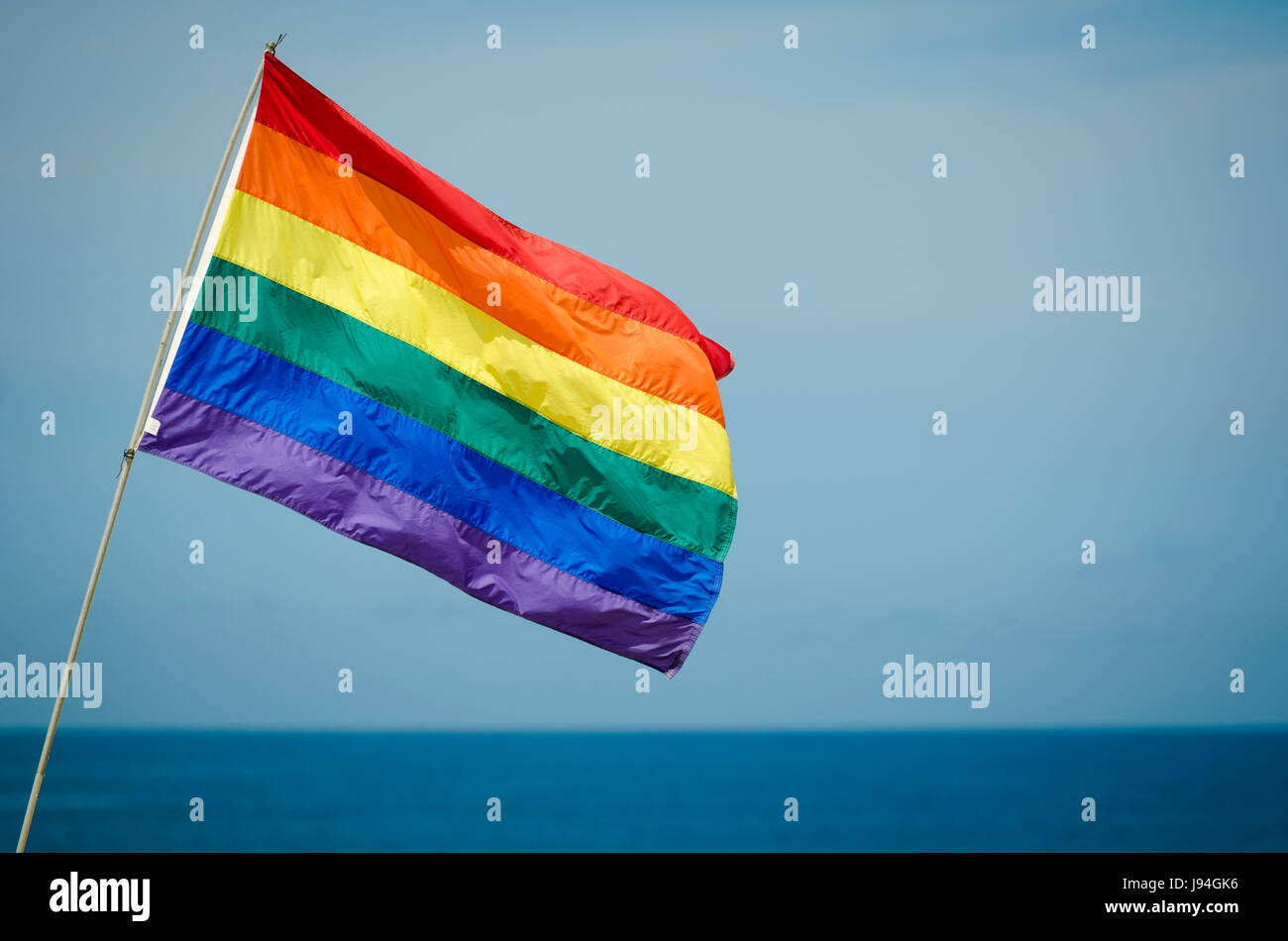 Gay pride rainbow flag flying extérieur à la lumière du soleil d'été au-dessus de l'horizon de l'océan dans Fire Island, New York Banque D'Images