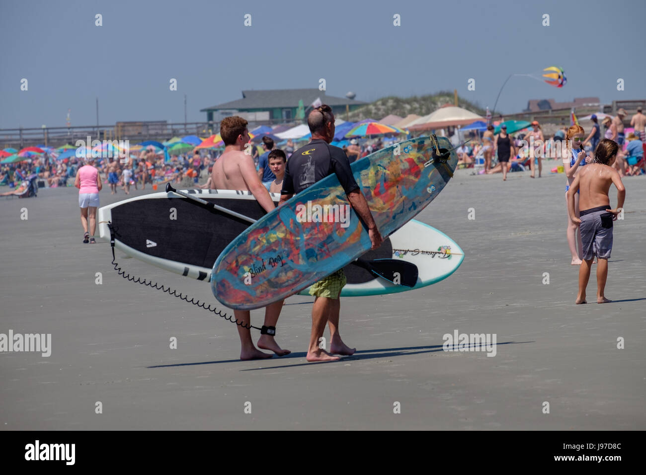 Surfer et Paddleboarder sur une plage bondée Banque D'Images